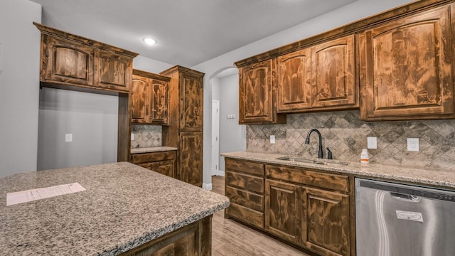 kitchen with dishwasher, backsplash, sink, light stone countertops, and light hardwood / wood-style floors