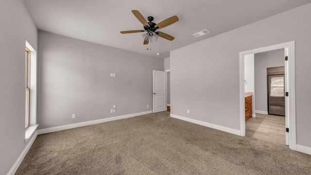 unfurnished bedroom with ceiling fan, light carpet, connected bathroom, and multiple windows