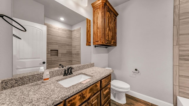 bathroom with vanity, toilet, wood-type flooring, and a tile shower