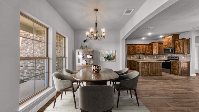 dining space featuring wood-type flooring and a notable chandelier