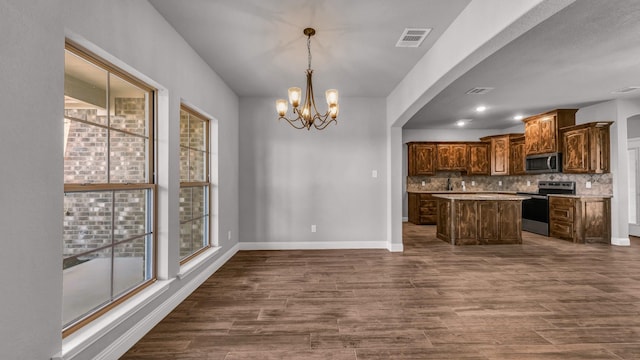 kitchen featuring pendant lighting, backsplash, an inviting chandelier, appliances with stainless steel finishes, and a kitchen island