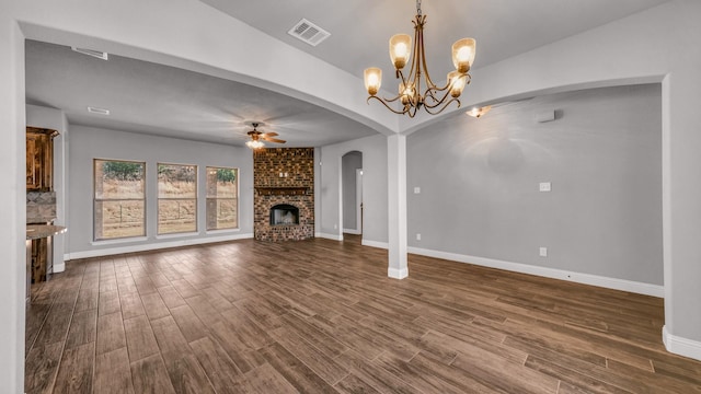 unfurnished living room featuring ceiling fan with notable chandelier, dark hardwood / wood-style flooring, and a fireplace