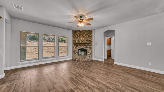 unfurnished living room featuring a fireplace, wood-type flooring, a textured ceiling, and ceiling fan