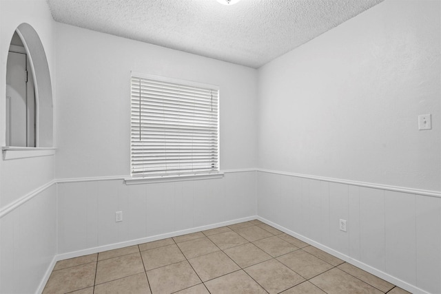 unfurnished room with light tile patterned floors and a textured ceiling