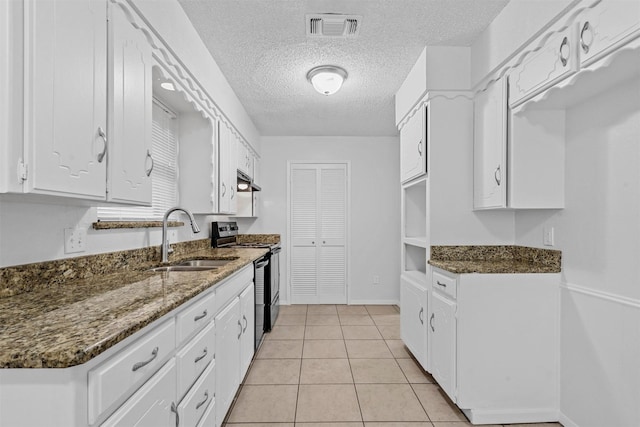 kitchen featuring black range with electric stovetop, white cabinetry, sink, dark stone counters, and light tile patterned flooring