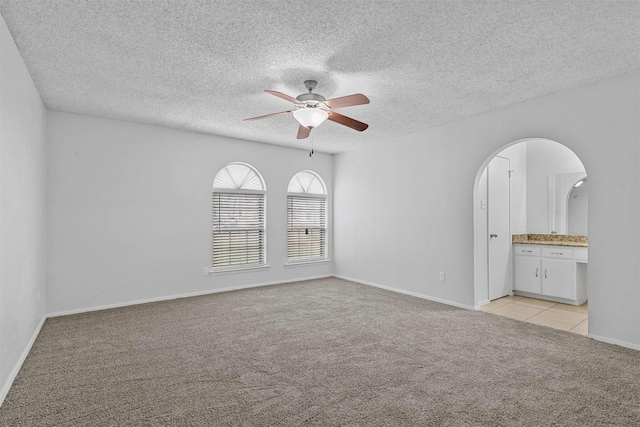 unfurnished room with ceiling fan, light colored carpet, and a textured ceiling