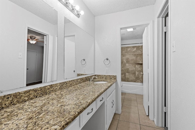 bathroom with ceiling fan, tile patterned floors, a textured ceiling, vanity, and tiled shower / bath