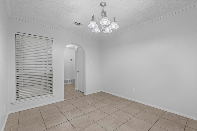 tiled spare room featuring a chandelier and a textured ceiling