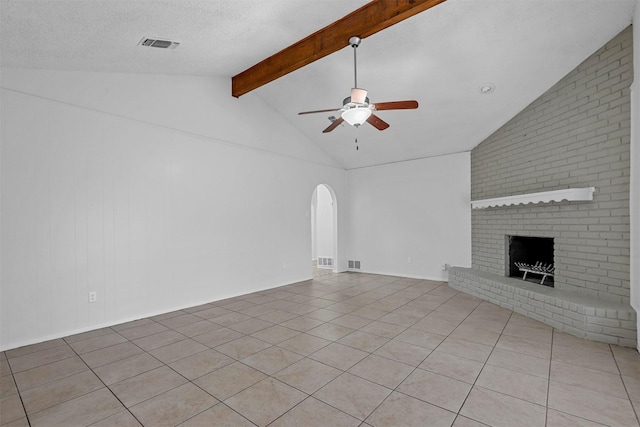 unfurnished living room with a fireplace, a textured ceiling, lofted ceiling with beams, and light tile patterned flooring