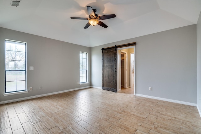 unfurnished room with a barn door, a raised ceiling, and ceiling fan