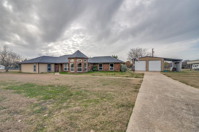 ranch-style house featuring a garage, an outbuilding, and a front lawn