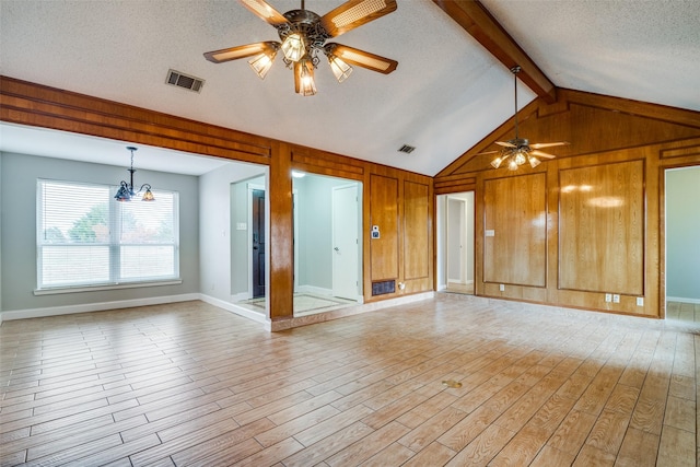 unfurnished living room with light wood-type flooring, ceiling fan with notable chandelier, a textured ceiling, vaulted ceiling with beams, and wood walls