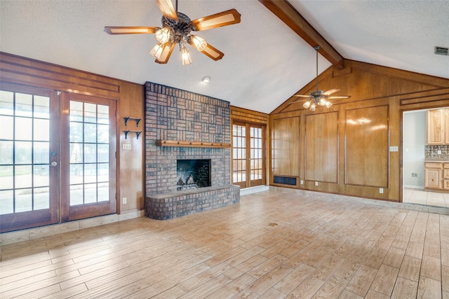 unfurnished living room with french doors, light hardwood / wood-style flooring, vaulted ceiling with beams, ceiling fan, and a fireplace