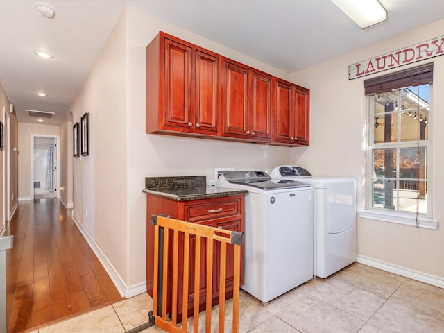 washroom featuring washing machine and clothes dryer, light tile patterned flooring, and cabinets