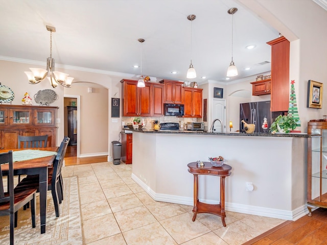 kitchen featuring black appliances, pendant lighting, kitchen peninsula, and a chandelier