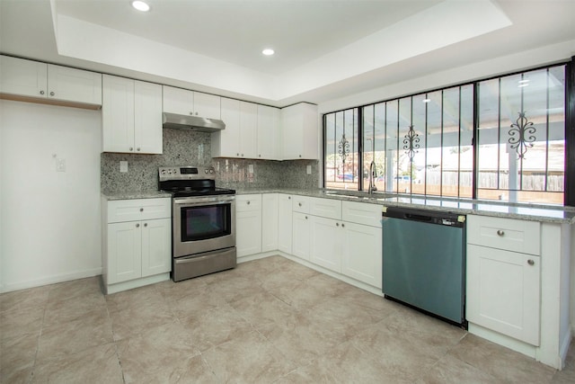 kitchen featuring light stone countertops, white cabinetry, appliances with stainless steel finishes, and a tray ceiling