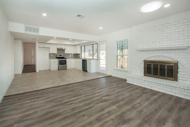 unfurnished living room featuring dark wood-type flooring and a brick fireplace