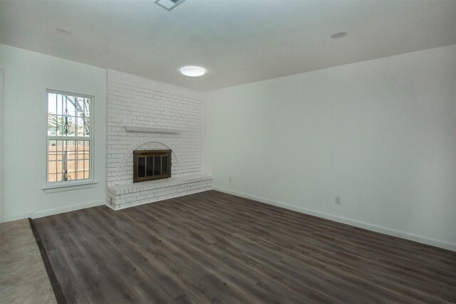 unfurnished living room featuring dark hardwood / wood-style flooring and a brick fireplace