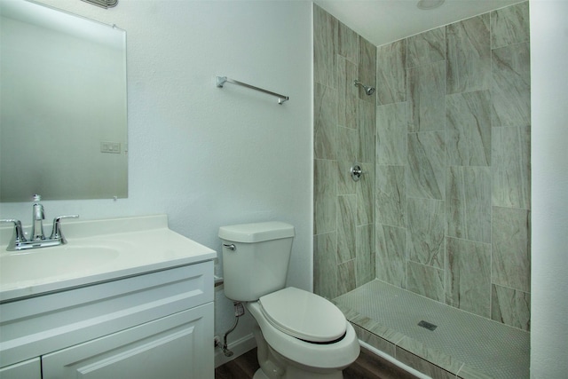 bathroom with a tile shower, vanity, and toilet