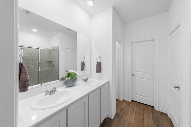 bathroom with hardwood / wood-style floors, vanity, and a shower with shower door