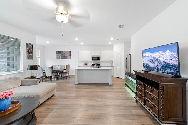 living room with ceiling fan and light wood-type flooring