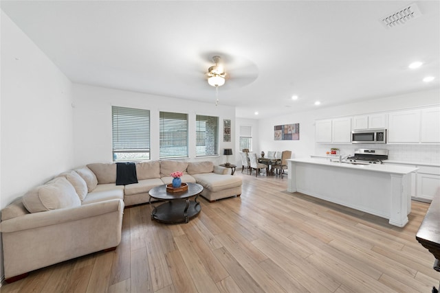 living room with ceiling fan and light hardwood / wood-style floors