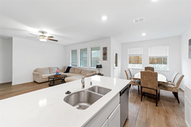 kitchen with stainless steel dishwasher, white cabinets, sink, and a wealth of natural light