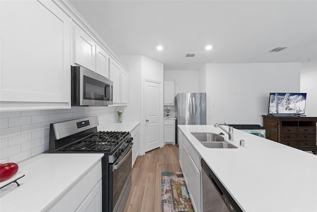 kitchen featuring sink, stainless steel appliances, tasteful backsplash, light hardwood / wood-style floors, and white cabinets