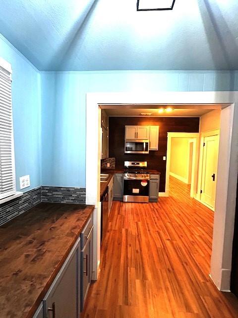 kitchen with wood-type flooring, a textured ceiling, stainless steel appliances, and gray cabinetry