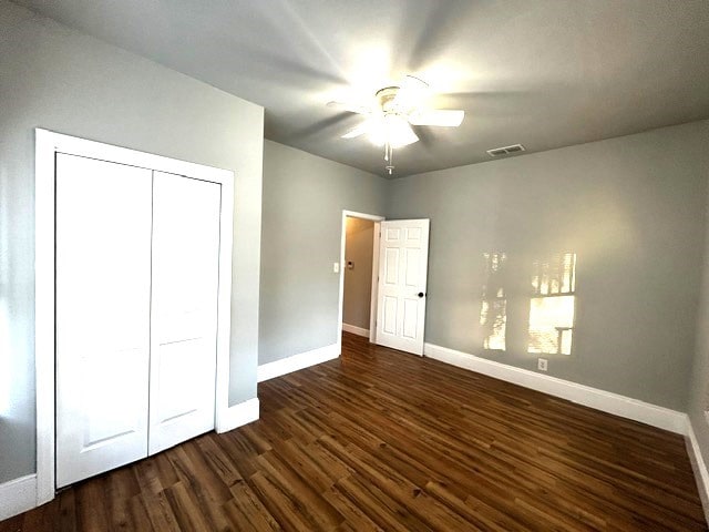 unfurnished bedroom featuring ceiling fan, dark hardwood / wood-style flooring, and a closet