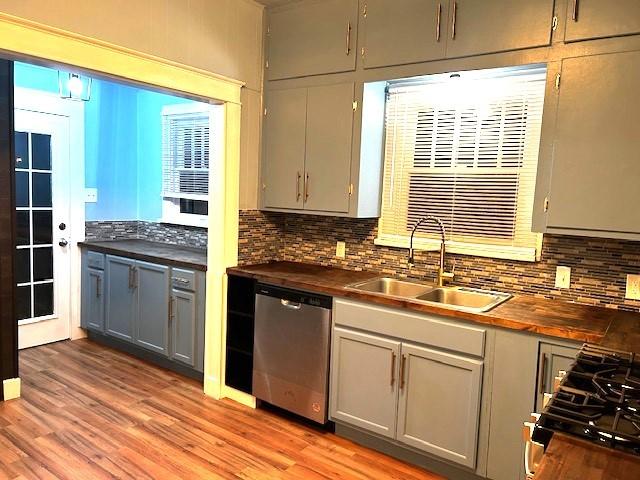 kitchen featuring wood counters, stainless steel dishwasher, gray cabinetry, sink, and range