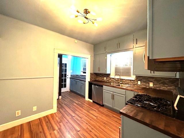 kitchen featuring an inviting chandelier, sink, light hardwood / wood-style flooring, stainless steel dishwasher, and gray cabinets