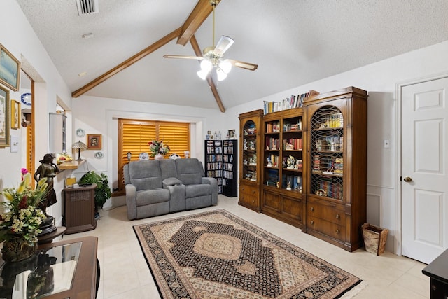 living room featuring vaulted ceiling with beams, ceiling fan, light tile patterned flooring, and a textured ceiling