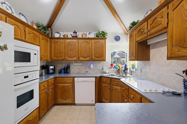 kitchen with a textured ceiling, sink, light tile patterned flooring, and white appliances