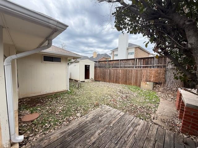 view of yard with a wooden deck and a storage shed