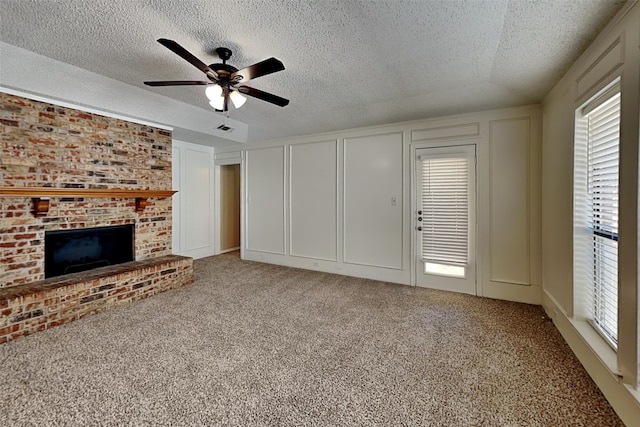 unfurnished living room featuring a brick fireplace, carpet, ceiling fan, and a healthy amount of sunlight