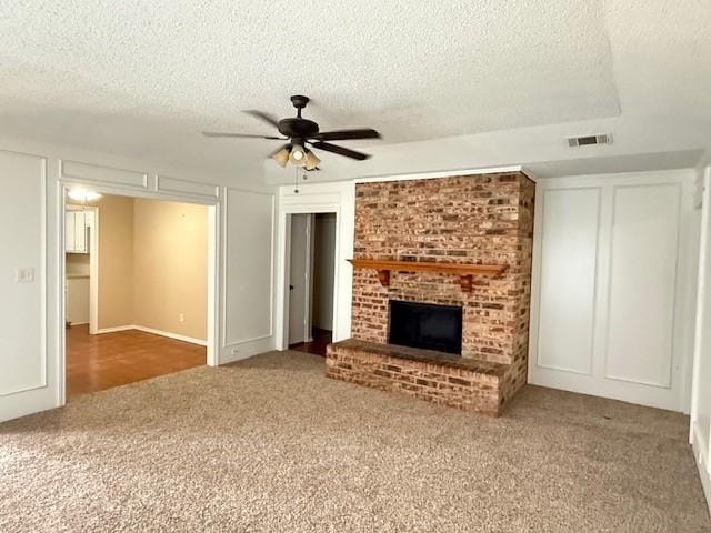 unfurnished living room featuring a fireplace, a textured ceiling, carpet, and ceiling fan