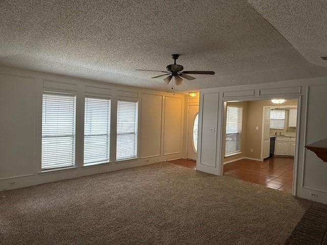 spare room with ceiling fan and dark colored carpet