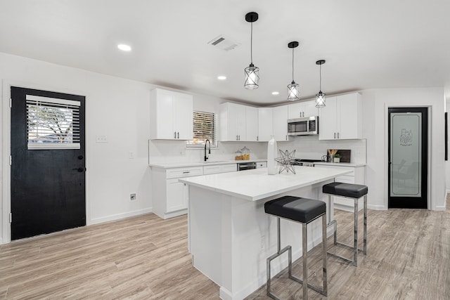 kitchen featuring a center island, white cabinetry, hanging light fixtures, and tasteful backsplash