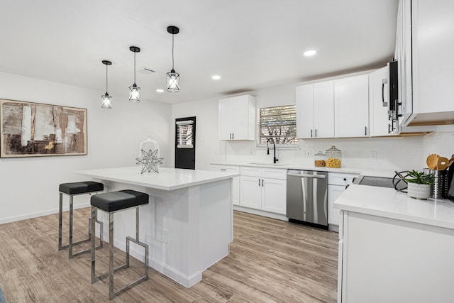 kitchen with white cabinetry, stainless steel dishwasher, a kitchen island, and sink