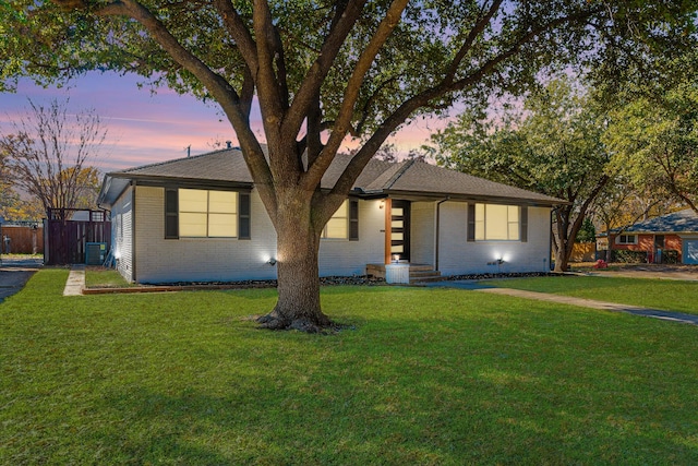 ranch-style home featuring central air condition unit and a lawn