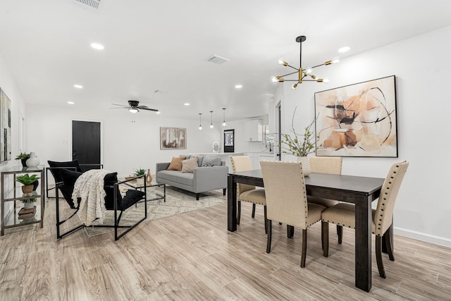 dining space featuring light hardwood / wood-style flooring and ceiling fan with notable chandelier