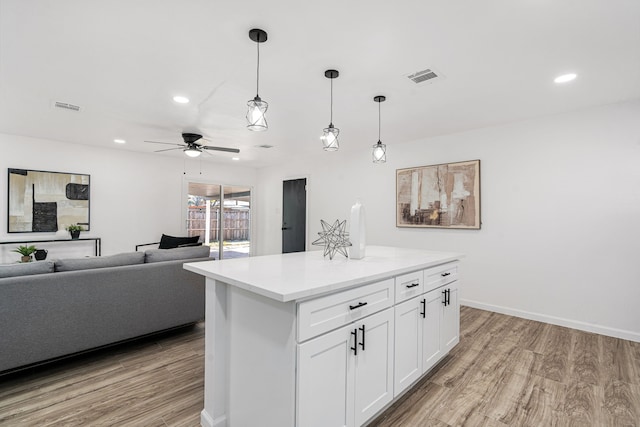 kitchen with a center island, light hardwood / wood-style flooring, ceiling fan, decorative light fixtures, and white cabinetry