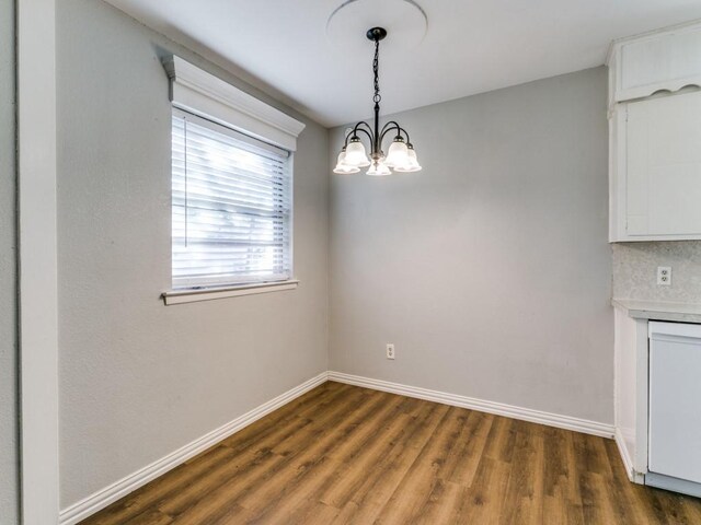 unfurnished dining area with an inviting chandelier and dark hardwood / wood-style floors