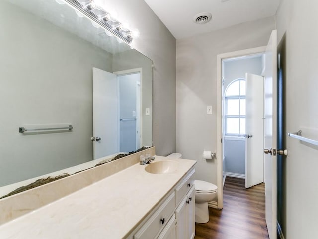 bathroom featuring toilet, vanity, and hardwood / wood-style floors