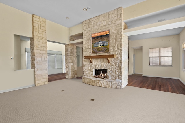 unfurnished living room with dark carpet and a stone fireplace