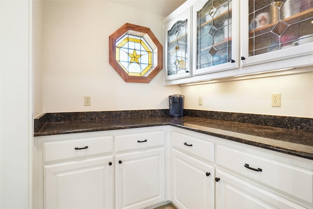 kitchen featuring dark stone countertops and white cabinets