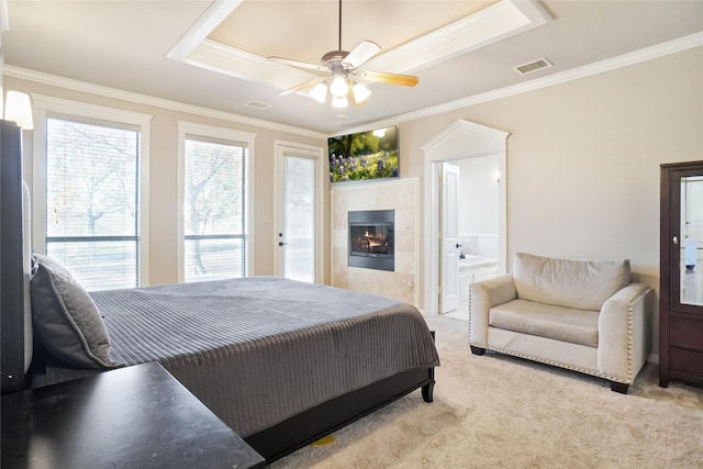 bedroom with connected bathroom, ceiling fan, a tile fireplace, light colored carpet, and ornamental molding