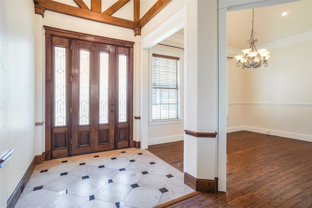 foyer entrance featuring vaulted ceiling with beams, crown molding, and an inviting chandelier