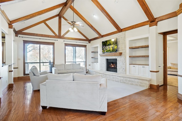 living room with high vaulted ceiling, ceiling fan, built in features, a fireplace, and beam ceiling